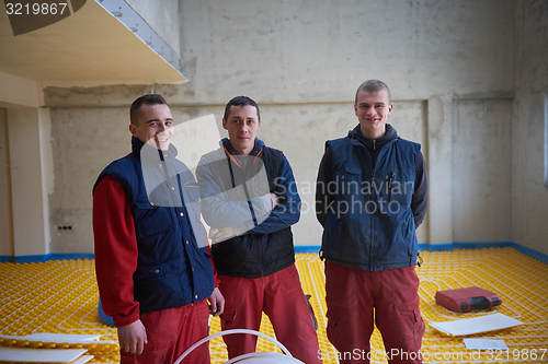 Image of workers installing underfloor heating system