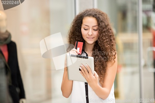 Image of Beautiful young girl paying by credit card for shopping 