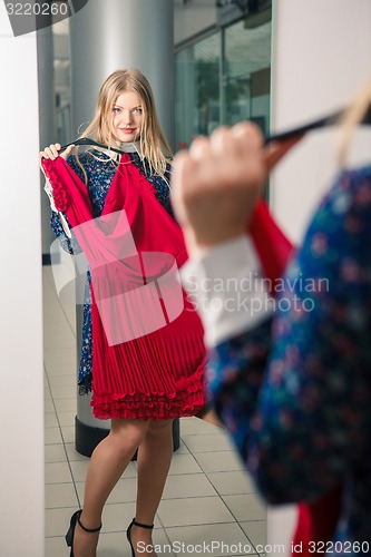 Image of Woman trying red dress shopping for clothing. 