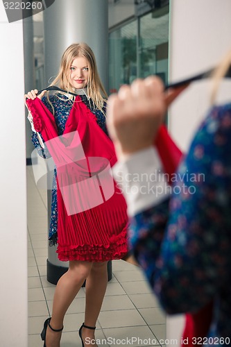 Image of Woman trying red dress shopping for clothing. 