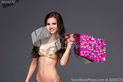 Image of Young woman with shopping bags and credit card on a gray background
