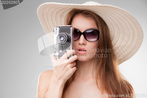 Image of Girl in broad-brimmed hat  and sunglasses with retro camera 