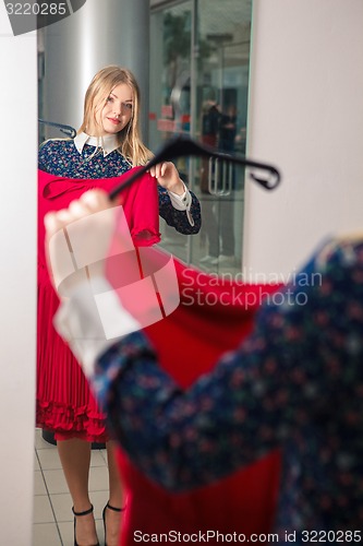 Image of Woman trying red dress shopping for clothing. 