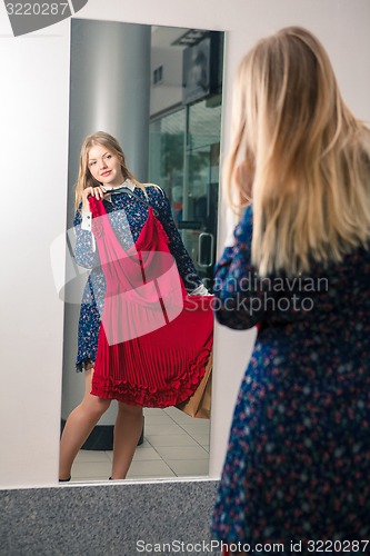 Image of Woman trying red dress shopping for clothing. 