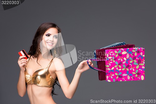 Image of Young woman with shopping bags and credit card on a gray background