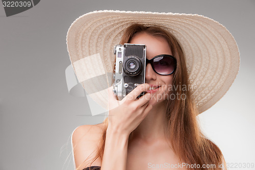 Image of Girl in broad-brimmed hat  and sunglasses with retro camera 