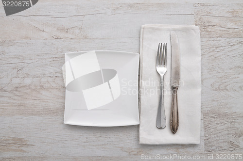 Image of Plate, cutlery and cloth on wood