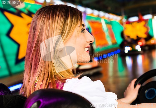 Image of Beautiful girl in an electric bumper car in amusement park