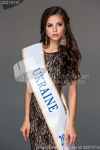 Image of Beautiful young brunette woman with her hair posing in a i long dress. Studio, on gray background