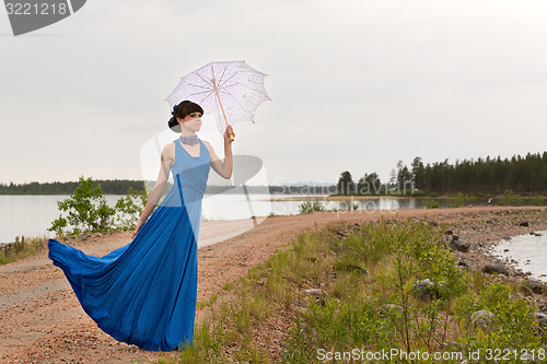 Image of A girl tries to keep a umbrella which pulls out a wind.