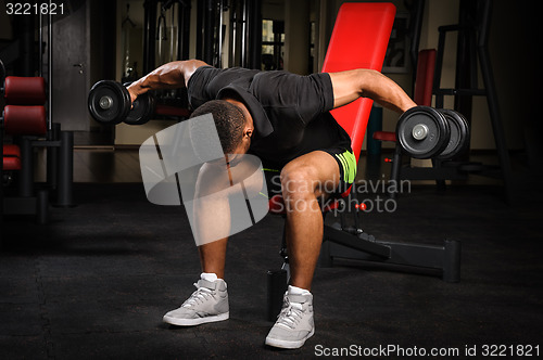 Image of Young man doing Seated Bent Over Dumbbell Reverse Fly workout in gym