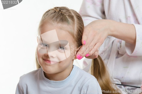 Image of Mom braids tails of hair six-year daughter