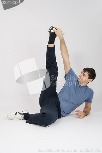 Image of Athlete stretches muscles of legs by raising