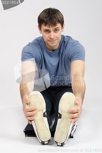 Image of The young man stretches muscles of legs