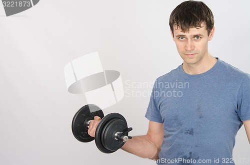 Image of Athlete pumps muscle of the right hand using dumbbells