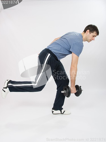 Image of athlete performs a slope with dumbbells standing on one leg