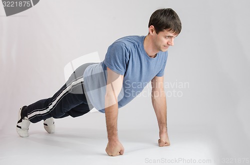 Image of Young guy pushed off the floor with their fists