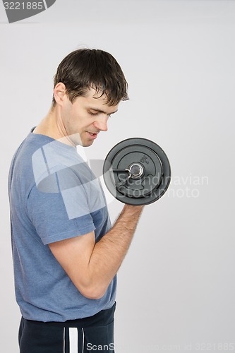 Image of Athlete looks at arm muscles under weight of dumbbell