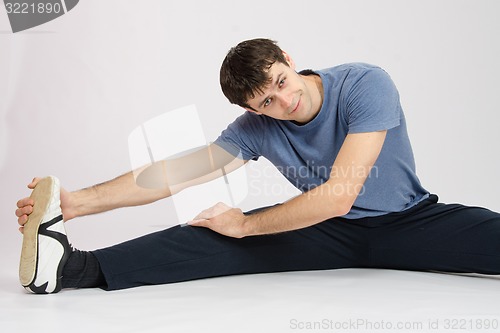 Image of Man in training stretches muscles of the right leg