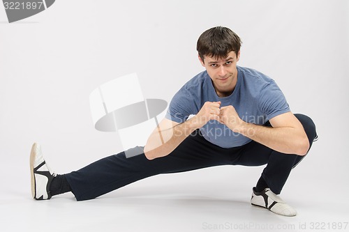 Image of Athlete crouching stretches the muscles of right leg