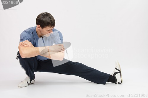 Image of Athlete crouching stretches muscles of left leg