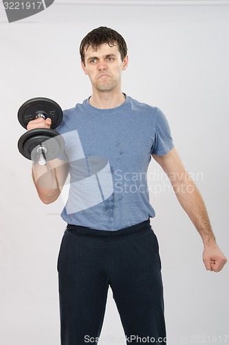 Image of athlete with a dumbbell effort raises his right hand