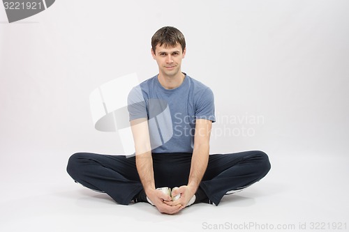 Image of Athlete sitting holding hands your feet