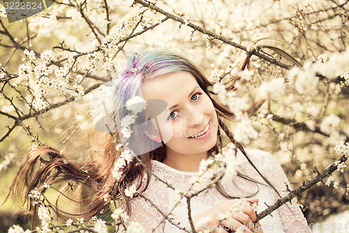 Image of Portrait of cheerful fashionable woman in spring blooming tree