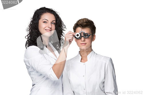 Image of Optometrist holding an eye test glasses and giving to young woman examination
