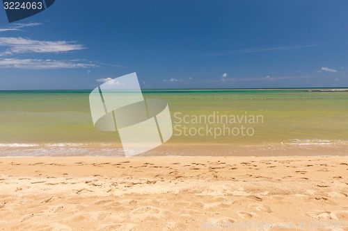 Image of Beach on tropical island. Clear blue water, sand, clouds. 