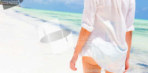 Image of Woman on the beach in white shirt. 