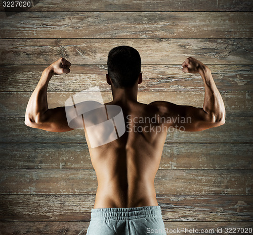 Image of young man or bodybuilder showing biceps