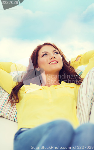 Image of smiling young woman lying on sofa at home