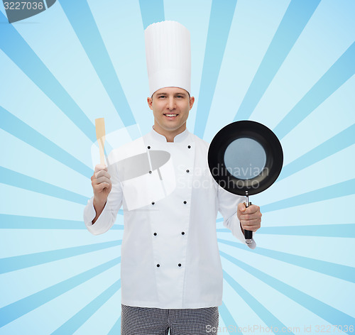 Image of happy male chef holding frying pan and spatula