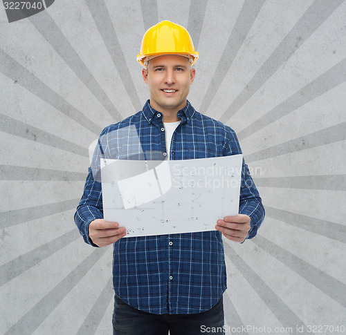 Image of smiling male builder in helmet with blueprint