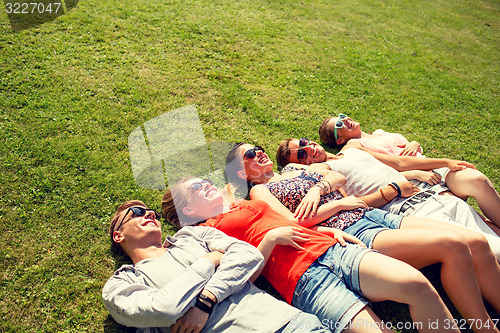 Image of group of smiling friends lying on grass outdoors