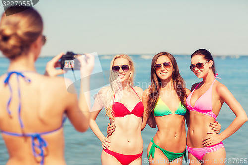 Image of group of smiling women photographing on beach