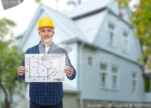 Image of smiling builder with blueprint over house