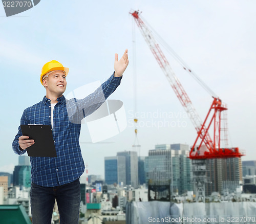 Image of smiling male builder in helmet with clipboard