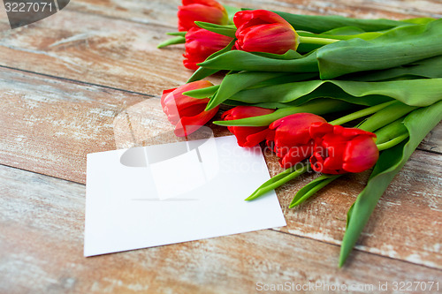 Image of close up of red tulips and blank paper or letter