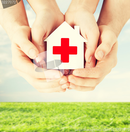 Image of hands holding paper house with red cross