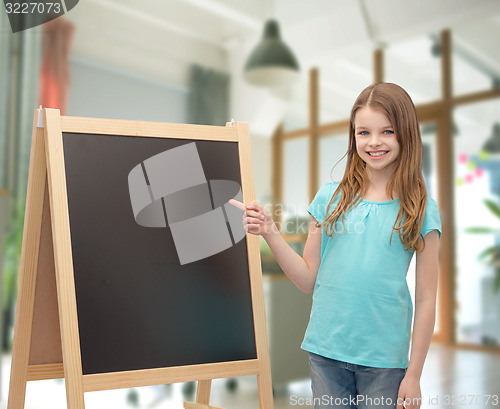 Image of happy little girl with blackboard and chalk