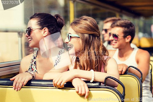 Image of group of smiling friends traveling by tour bus