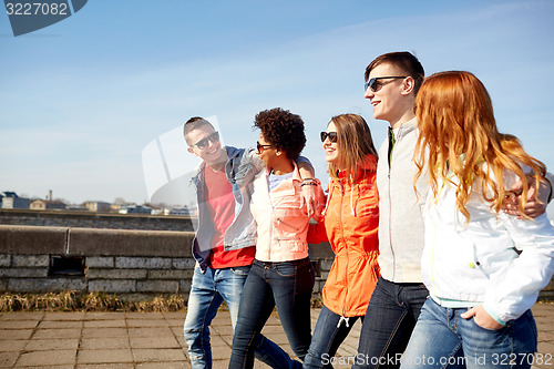 Image of happy teenage friends walking along city street