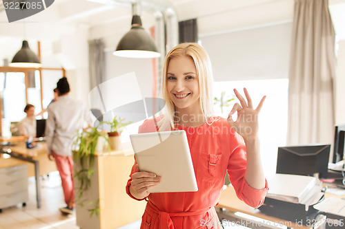 Image of woman with tablet pc showing ok sign at office