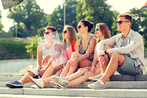 Image of group of smiling friends sitting on city square