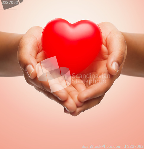 Image of close up of female hands holding small red heart