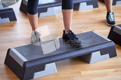 Image of close up of women exercising with steppers in gym