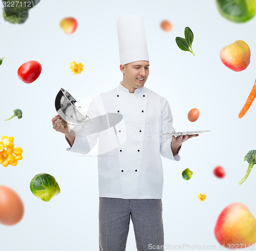 Image of happy male chef cook opening cloche