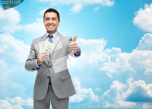 Image of smiling businessman with money showing thumbs up